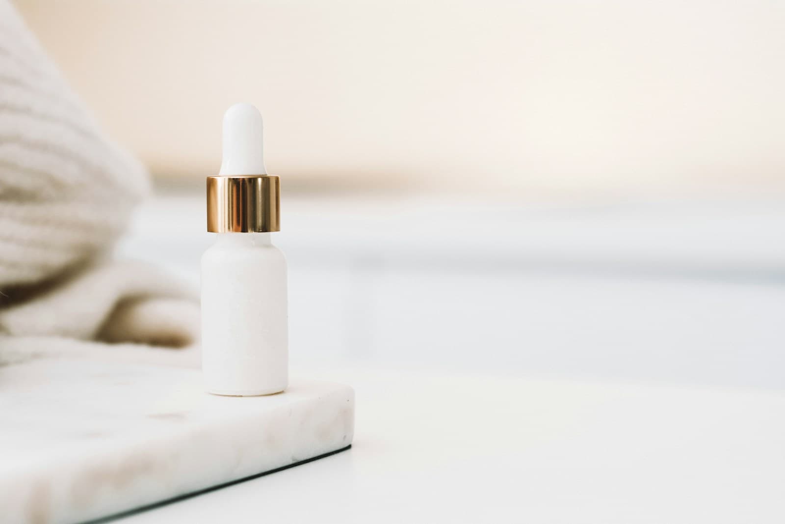 Minimalist white dropper bottle with brass collar on a marble tray — representative of how Pepoderma ships Snap-8 (Acetyl Octapeptide-3) as a finished-product-ready cosmetic active.